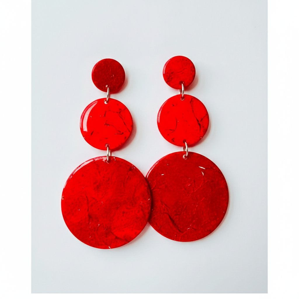 Flat lay of red polymer clay earrings on neutral background, modern statement accessory.